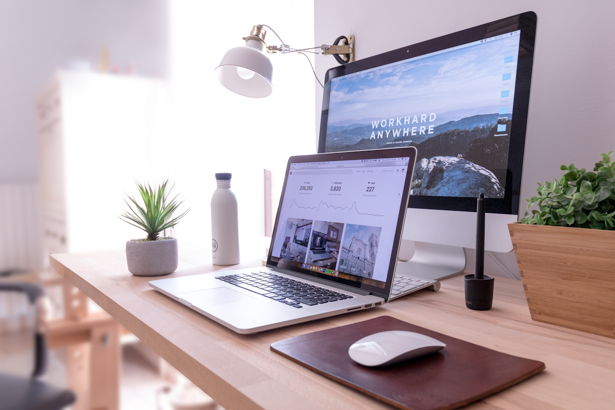 A laptop and desktop monitor in a bright creative workspace